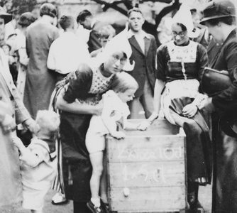 876695 Afbeelding van twee medewerksters van het Franciscus Liefdewerk in Volendammer klederdracht, bij een grabbelton ...